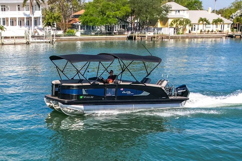 Slide: The Image of 2024 Barletta L23U pontoon boat cruising on a scenic waterway near waterfront homes. - 78