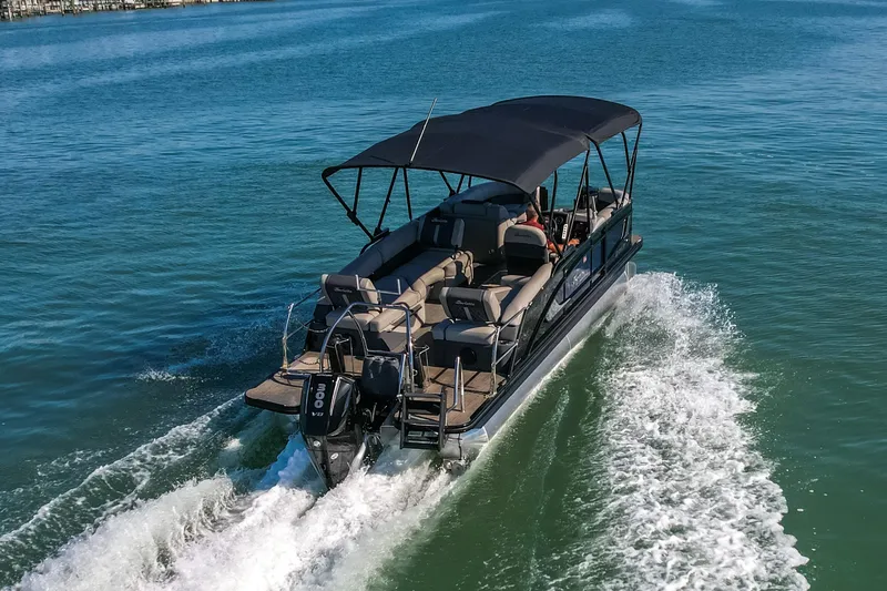 Slide: The Image of 2024 Barletta L23U pontoon boat cruising on open water with canopy and powerful engine. - 79