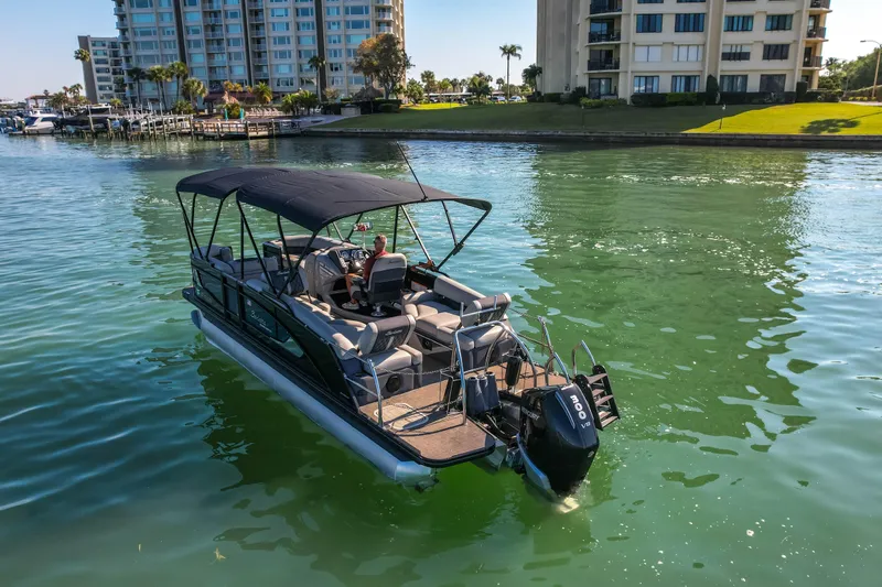 Slide: The Image of 2024 Barletta L23U pontoon boat on calm water near waterfront buildings. - 86