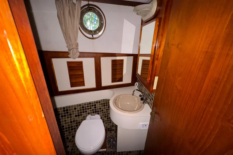 Slide: The Image of Compact bathroom with wooden accents and porthole window on 1982 Virpack Steel Hull boat. - 21
