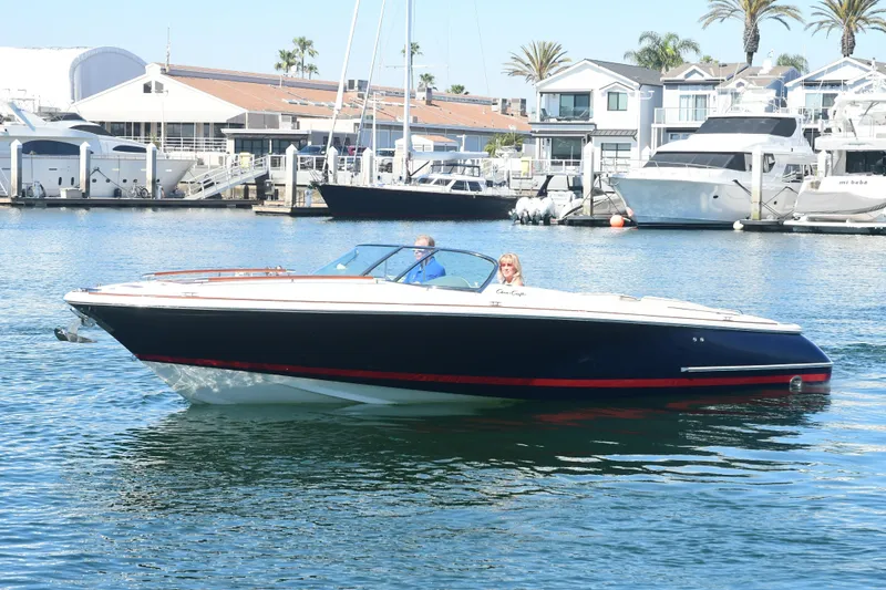 Slide: The Image of 2005 Chris-Craft Corsair 28 boat cruising in a marina with yachts and palm trees. - 6