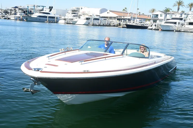 Slide: The Image of 2005 Chris-Craft Corsair 28 boat cruising in a marina with two passengers onboard. - 8