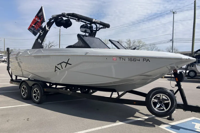 Slide: The Image of 2020 ATX Surf Boats 24 Type-S on trailer, parked outdoors with flag displayed. - 5