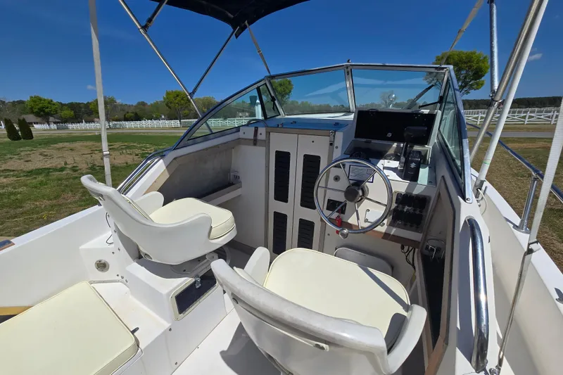 Slide: The Image of 1992 Grady White 226 boat interior with steering wheel and seating under blue sky. - 13