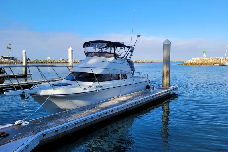 Slide: The Image of 2001 Skipjack 262 Flybridge boat docked in a marina under clear blue skies. - 10