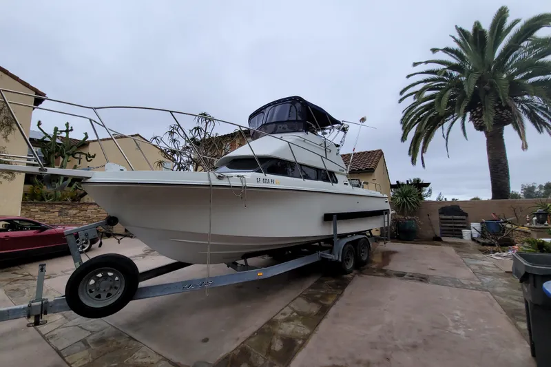 Slide: The Image of 2001 Skipjack 262 Flybridge boat on trailer in a driveway with palm trees. - 11