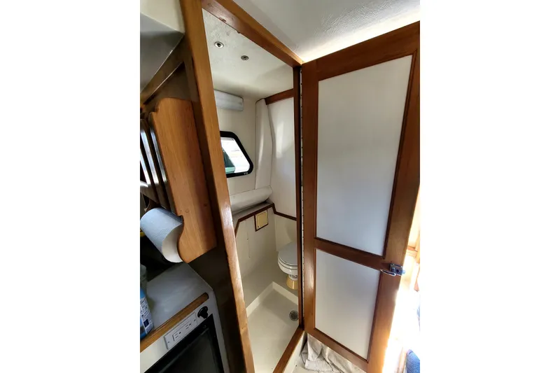 Slide: The Image of Interior of 2001 Skipjack 262 Flybridge boat, featuring a compact bathroom with wooden accents. - 19