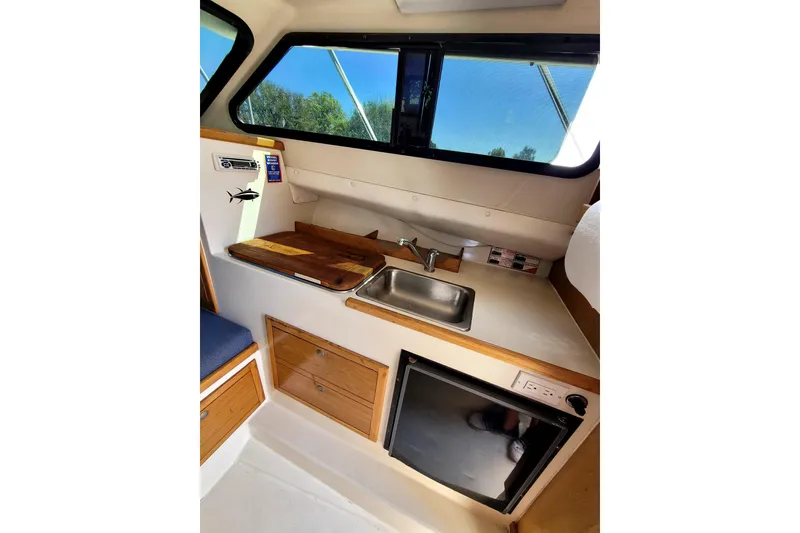 Slide: The Image of Interior of 2001 Skipjack 262 Flybridge boat with kitchenette, sink, and storage. - 23