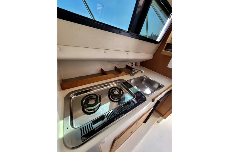 Slide: The Image of Compact kitchen area in a 2001 Skipjack 262 Flybridge boat with stove and sink. - 24