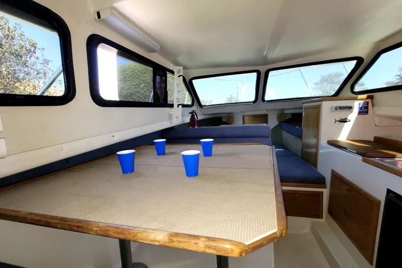 Slide: The Image of Interior of 2001 Skipjack 262 Flybridge boat with table and blue cups. - 28