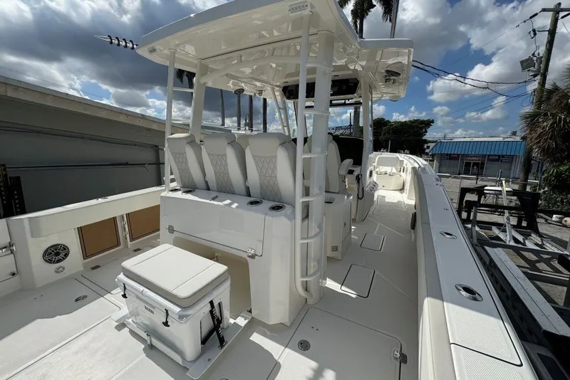 Slide: The Image of 2026 World Cat 400 CC-X boat interior with seating and storage, under a partly cloudy sky. - 12