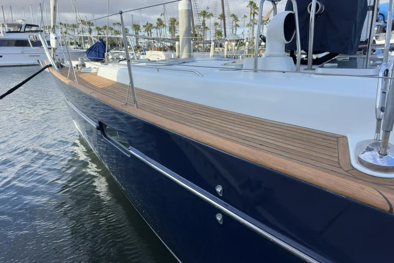 Slide: The Image of 2003 Beneteau 57 yacht with sleek blue hull and wooden deck in marina. - 101