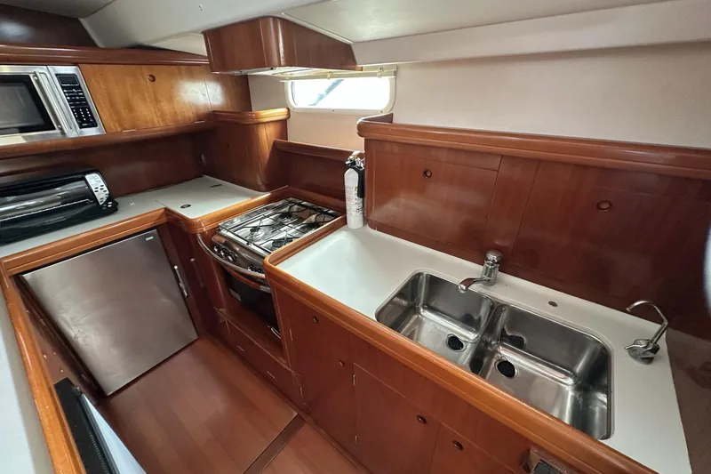 Slide: The Image of 2003 Beneteau 57 yacht kitchen with stove, sink, and wooden cabinetry. - 26