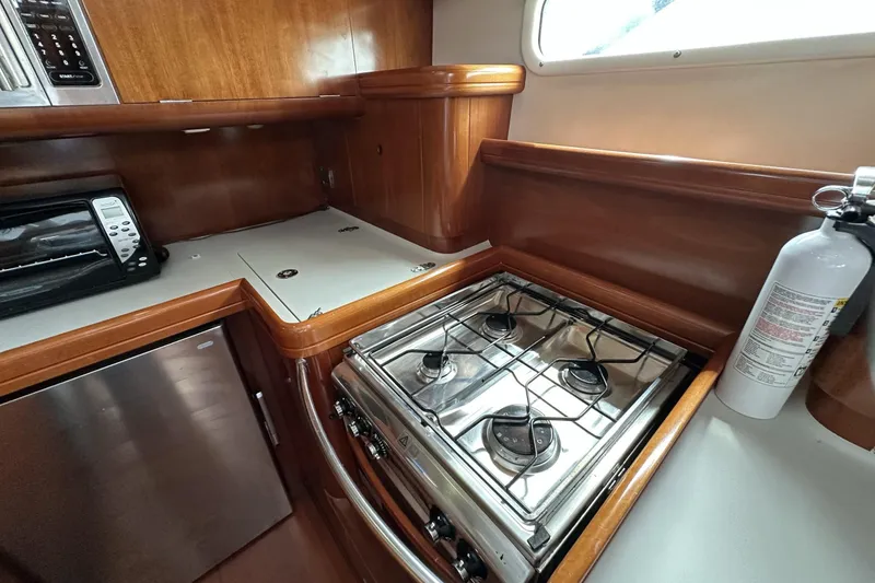 Slide: The Image of Galley kitchen in 2003 Beneteau 57 yacht with stove, fridge, and fire extinguisher. - 29