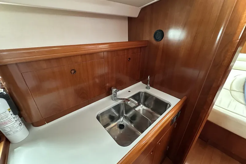 Slide: The Image of Galley sink area in 2003 Beneteau 57 yacht with wooden cabinetry and stainless steel sink. - 31