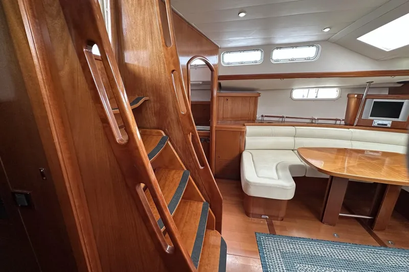 Slide: The Image of Interior of 2003 Beneteau 57 yacht with wooden stairs, dining area, and built-in seating. - 33