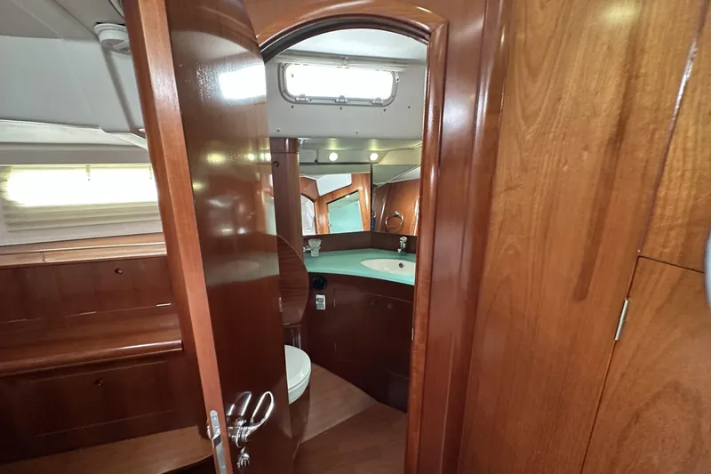 Slide: The Image of Interior of 2003 Beneteau 57 yacht showing wooden cabinetry and bathroom area. - 44