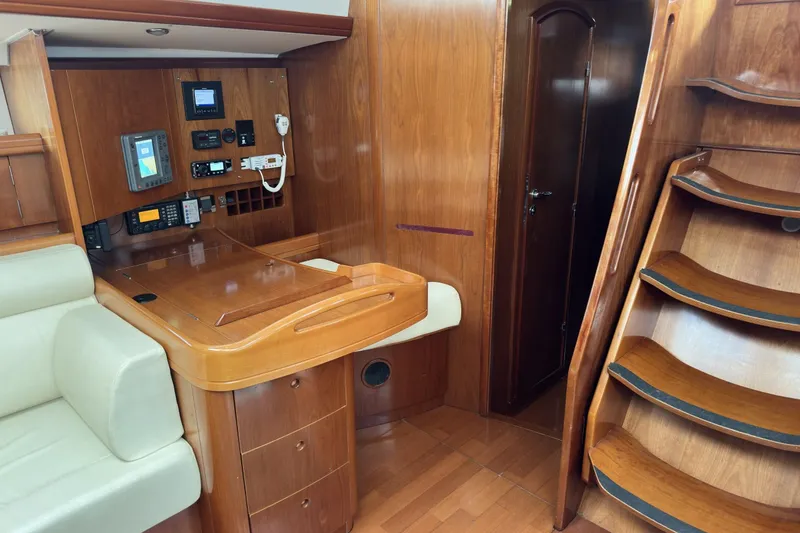 Slide: The Image of Interior of a 2003 Beneteau 57 yacht featuring a navigation station and wooden staircase. - 55