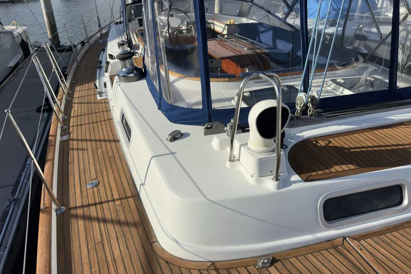 Slide: The Image of Deck view of a 2003 Beneteau 57 sailboat with teak flooring and blue canopy. - 79