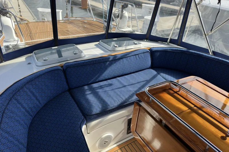 Slide: The Image of Luxurious seating area on a 2003 Beneteau 57 yacht with blue cushions and wooden table. - 87