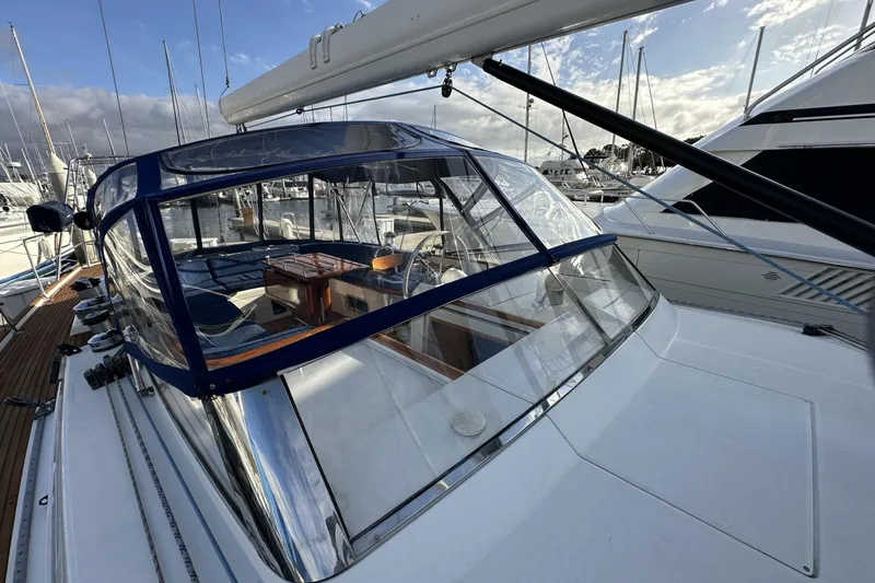 Slide: The Image of 2003 Beneteau 57 yacht with blue canopy, docked at marina under cloudy sky. - 97