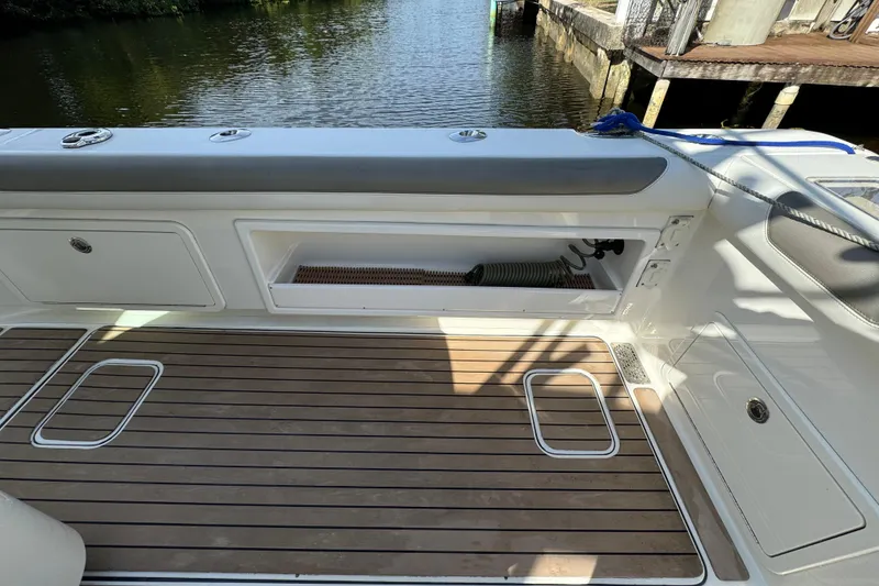 Slide: The Image of 2023 World Cat 325 CC boat deck with storage compartments and teak flooring. - 15