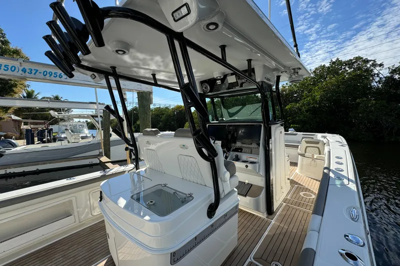 Slide: The Image of 2023 World Cat 325 CC boat interior with modern helm and seating, docked near lush greenery. - 26