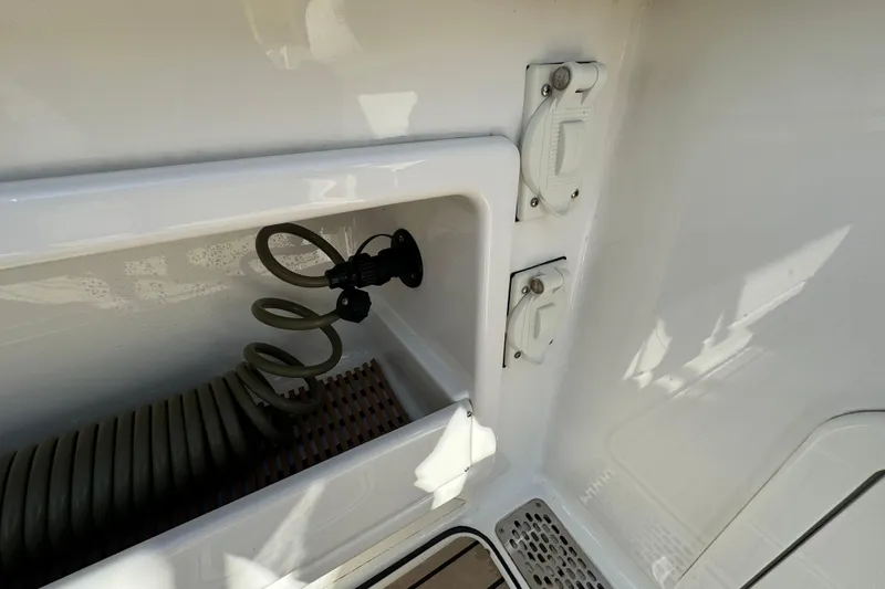 Slide: The Image of 2023 World Cat 325 CC boat hose storage compartment with coiled hose and outlets. - 37