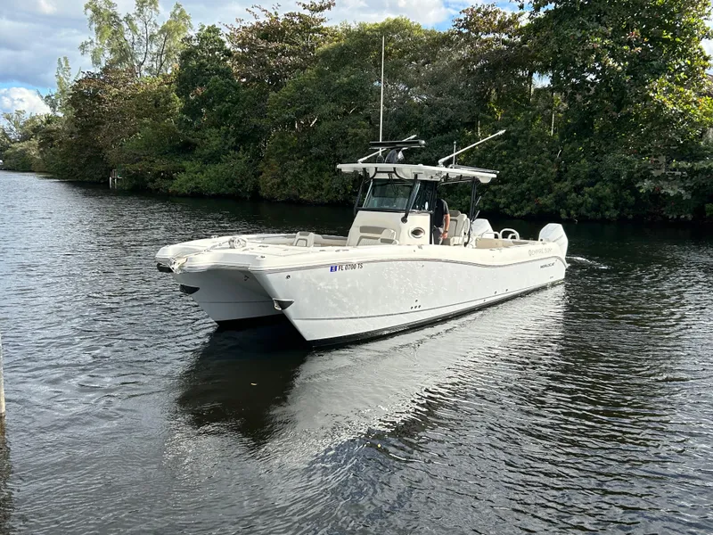 Slide: The Image of 2023 World Cat 325 CC boat cruising on a calm river, surrounded by lush greenery. - 4