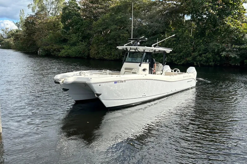 Slide: The Image of 2023 World Cat 325 CC boat cruising on a calm river surrounded by lush greenery. - 9