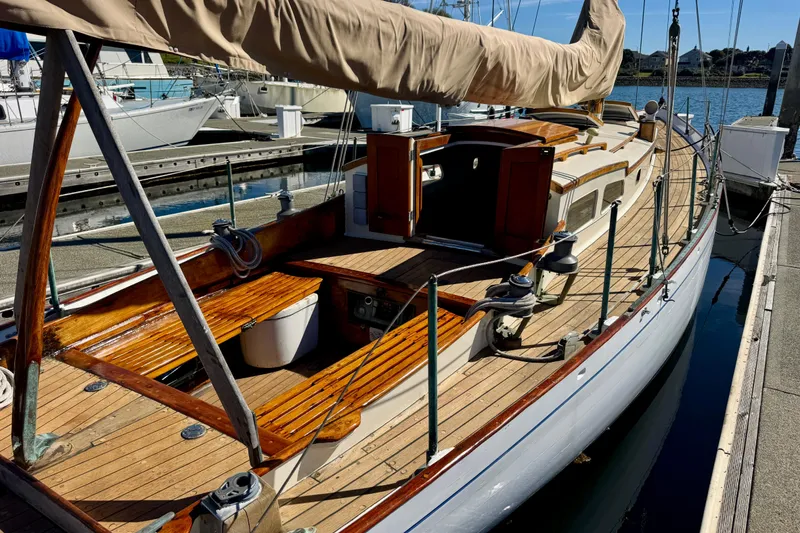 Slide: The Image of Classic 1946 Phillip Rhodes 42 sailboat docked, showcasing wooden deck and open cabin. - 11