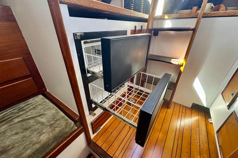 Slide: The Image of Vintage Phillip Rhodes 42 yacht interior with open storage drawers, wooden flooring, and ladder. - 28