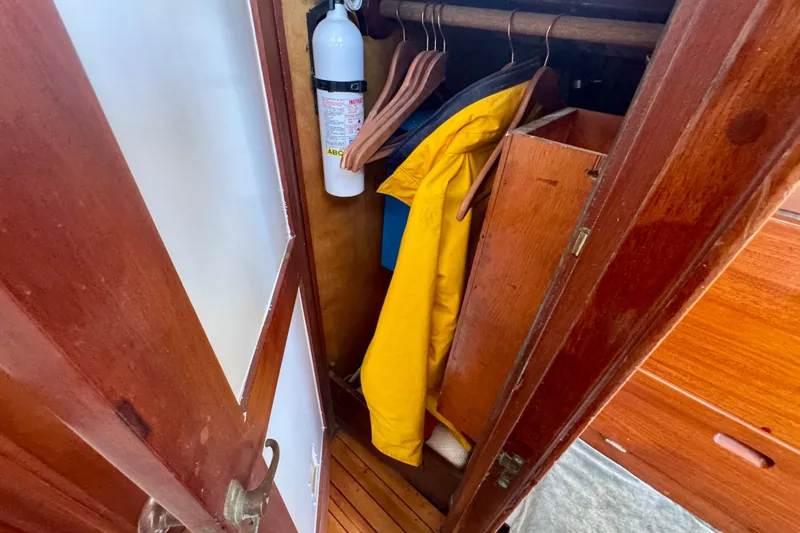 Slide: The Image of Wooden closet on a 1946 Phillip Rhodes 42 boat, featuring a yellow jacket and fire extinguisher. - 33