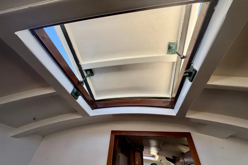 Slide: The Image of Open hatch on a 1946 Phillip Rhodes 42 sailboat, showcasing wooden frame and sky view. - 37