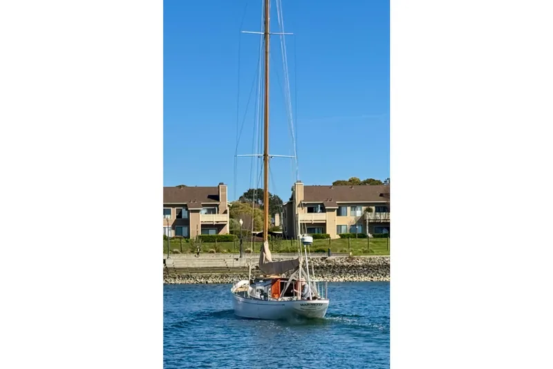 Slide: The Image of Sailboat "Phillip Rhodes 42" from 1946 on calm water near residential buildings. - 5