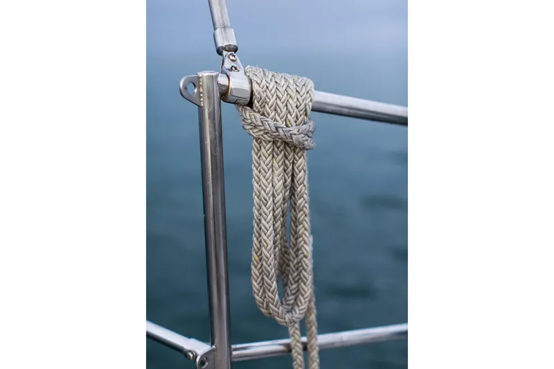 Slide: The Image of Braided rope secured on a Sundeer 56 sailboat railing, 1995 model, over water. - 14
