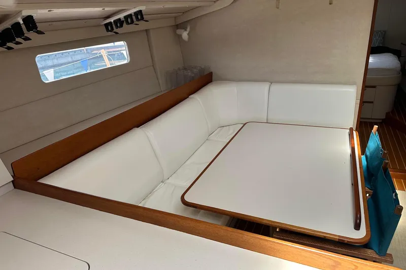 Slide: The Image of Interior of a 1995 Sundeer 56 yacht with white seating and wooden table. - 35