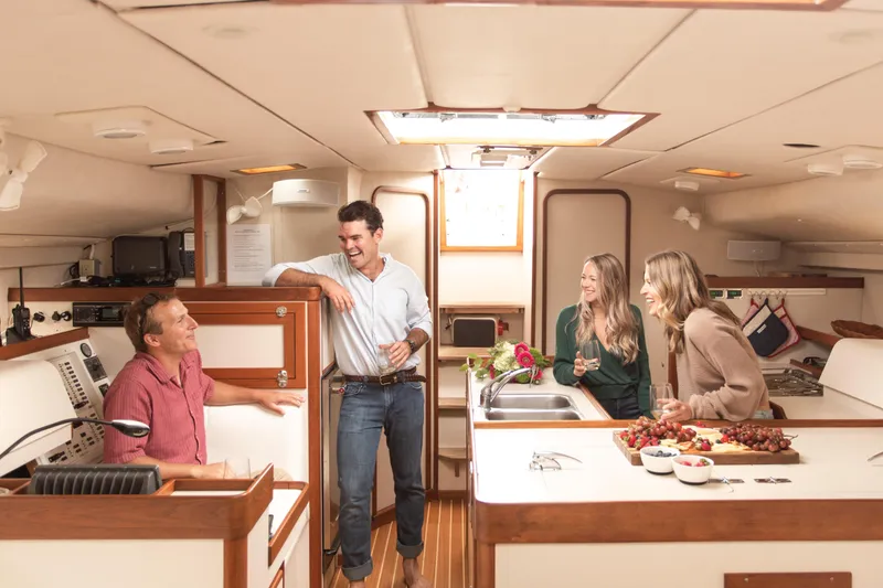 Slide: The Image of Four people enjoying a conversation in a 1995 Sundeer 56 yacht's cozy kitchen area. - 42