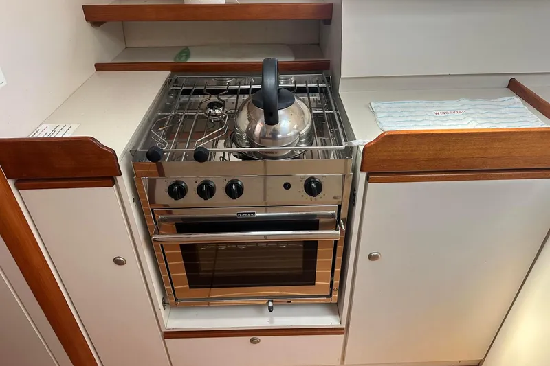 Slide: The Image of Compact kitchen with stainless steel stove and kettle, aboard a 1995 Sundeer 56 yacht. - 48