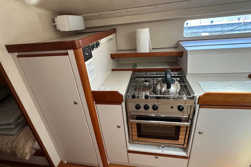 Slide: The Image of Compact kitchen in a 1995 Sundeer 56 yacht with stove, kettle, and storage cabinets. - 49