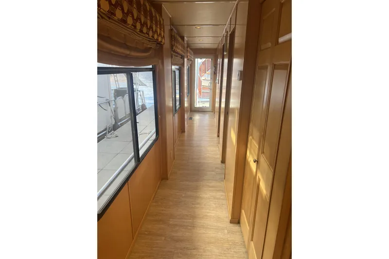 Slide: The Image of Narrow hallway inside 2007 American Waterways Sundancer, featuring wooden flooring and large windows. - 11
