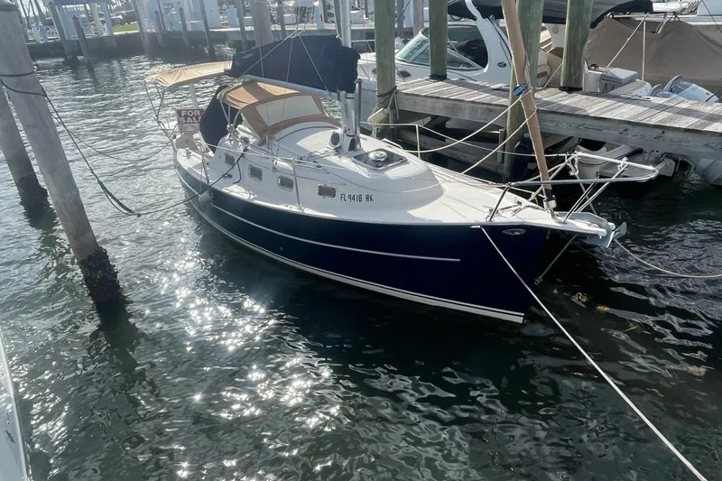 The Image of 2013 Hake Seaward 26RK sailboat docked, for sale, with blue hull and tan canopy. - 0