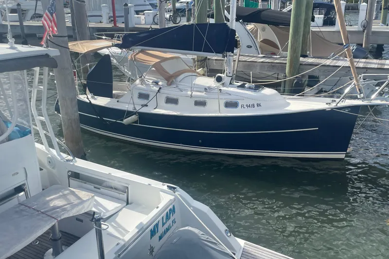 Slide: The Image of 2013 Hake Seaward 26RK sailboat docked in marina, featuring sleek navy hull. - 1
