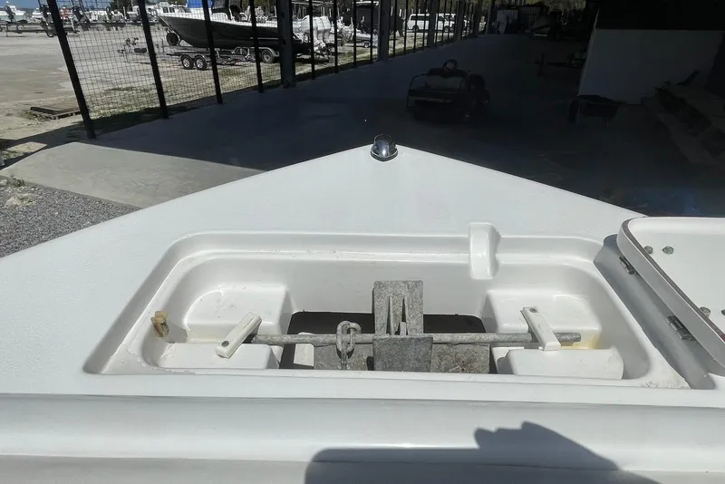 Slide: The Image of 2013 Sea Hunt Escape 211 LE boat anchor compartment in a marina setting. - 13