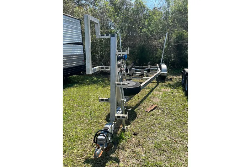 Slide: The Image of 2013 Sea Hunt Escape 211 LE boat trailer on grassy area, surrounded by trees. - 15