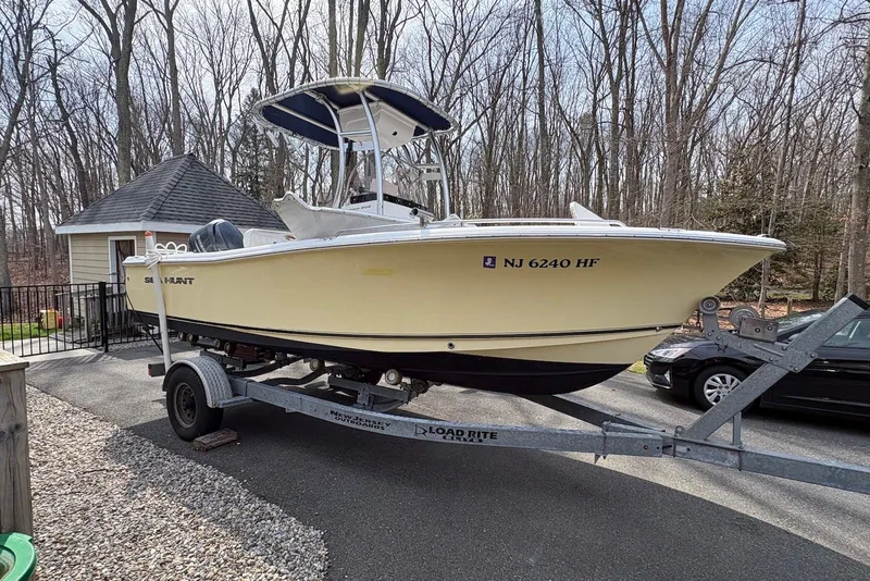 Slide: The Image of 2014 Sea Hunt Triton 202 boat on trailer, parked in driveway near wooded area. - 7