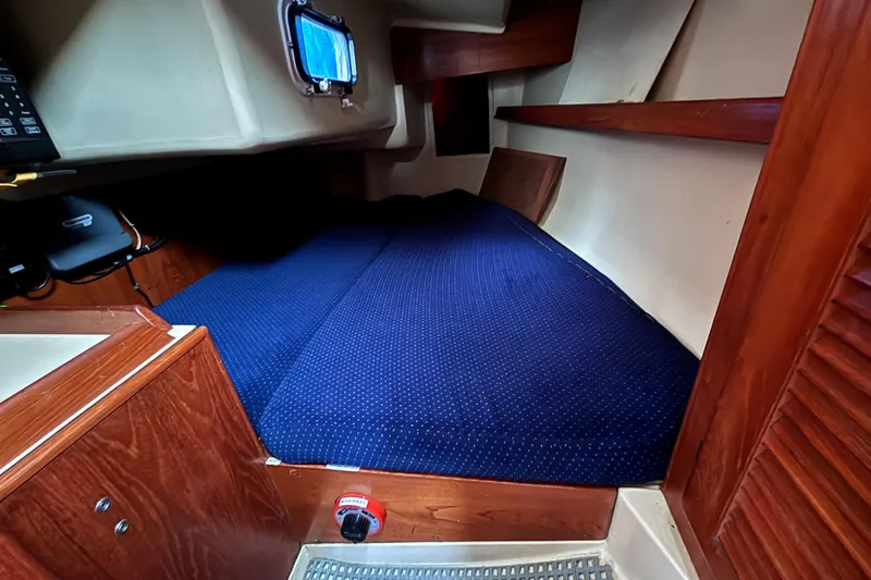 Slide: The Image of Interior cabin of a 1986 Pearson 28 sailboat with blue bedding and wooden accents. - 11