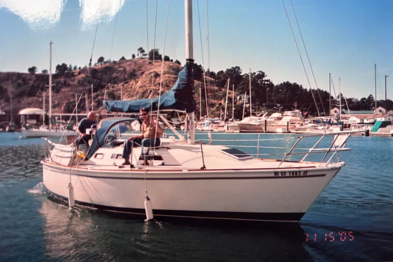 Slide: The Image of Sailboat Pearson 28, 1986 model, docked in a marina with scenic hillside background. - 2