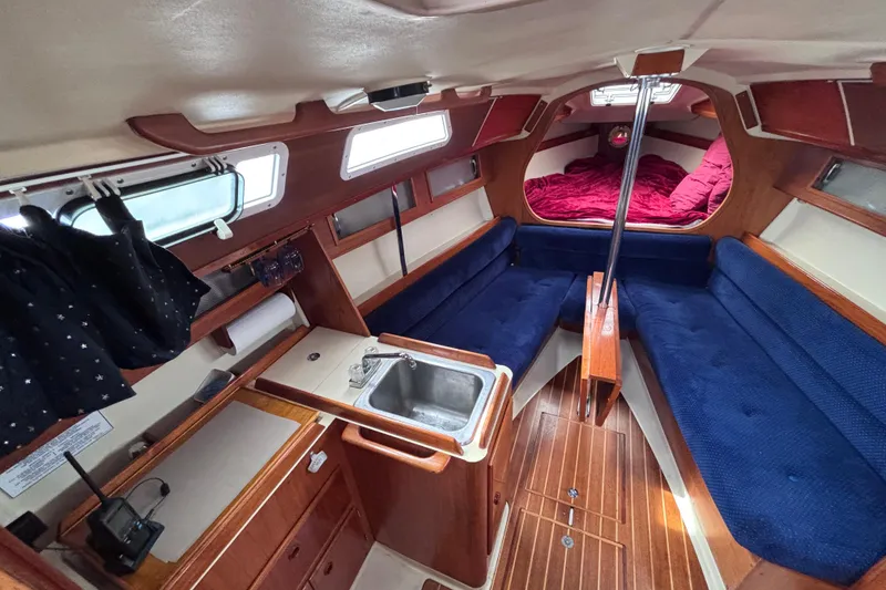 Slide: The Image of Interior of 1986 Pearson 28 sailboat with blue seating and compact kitchen area. - 7