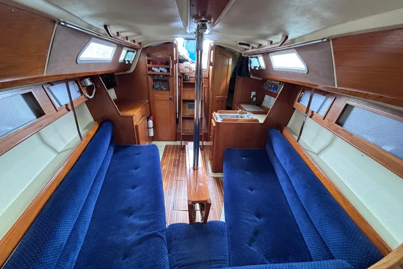 Slide: The Image of Interior of a 1986 Pearson 28 sailboat with blue seating and wooden finishes. - 8